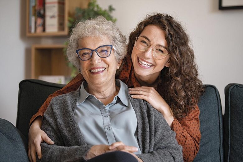 Happy grandmother with smiling granddaughter at home
