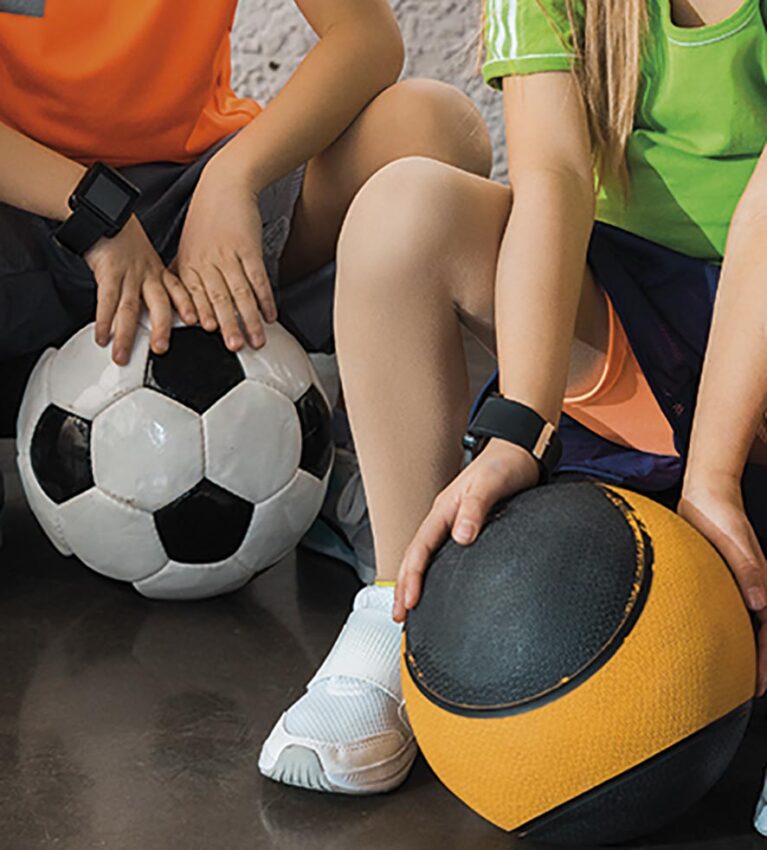 Cropped view of children sitting on step platforms with balls in