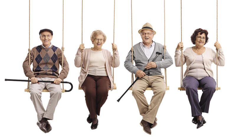 Cheerful seniors sitting on wooden swings and looking at the cam