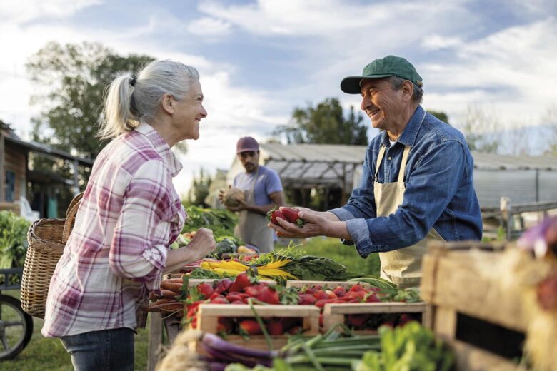 Happy farmer selling organic strawberries to a client at a Farmer's Market