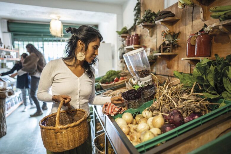 Mid adult woman buying vegetables at small local store