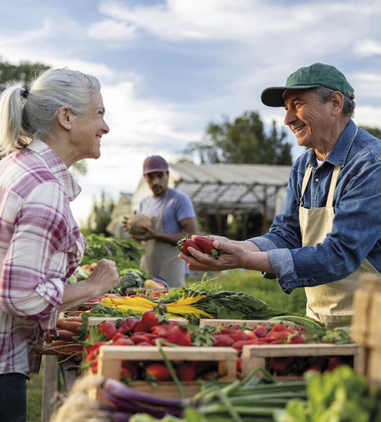 Happy farmer selling organic strawberries to a client at a Farmer's Market