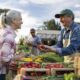 Happy farmer selling organic strawberries to a client at a Farmer's Market